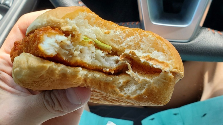 A hand holds a half-eaten Arby's fish sandwich