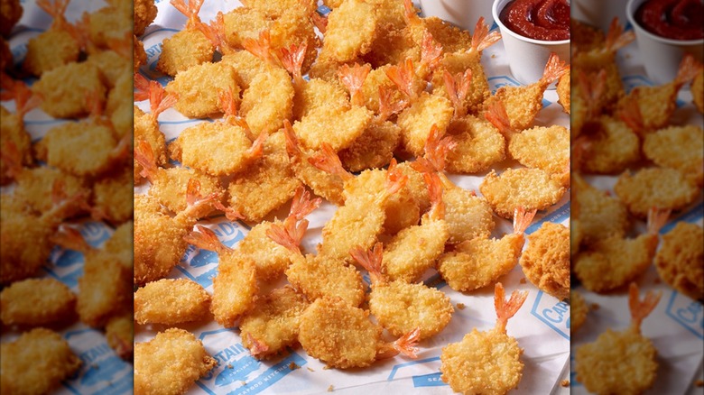 Captain D's Butterly Shrimp spread out on restaurant-printed paper with sauce.