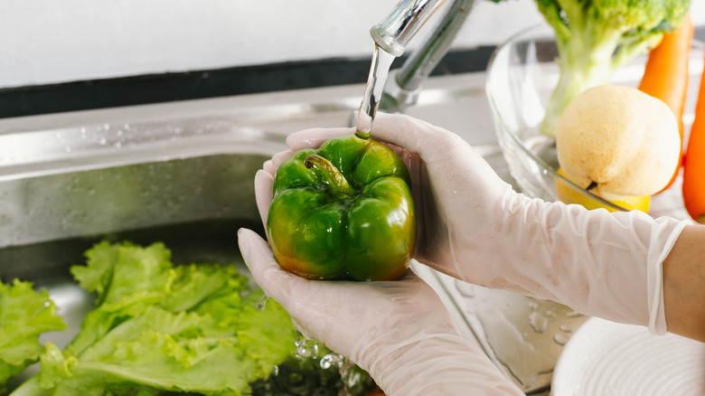 Person with gloves washing vegetables