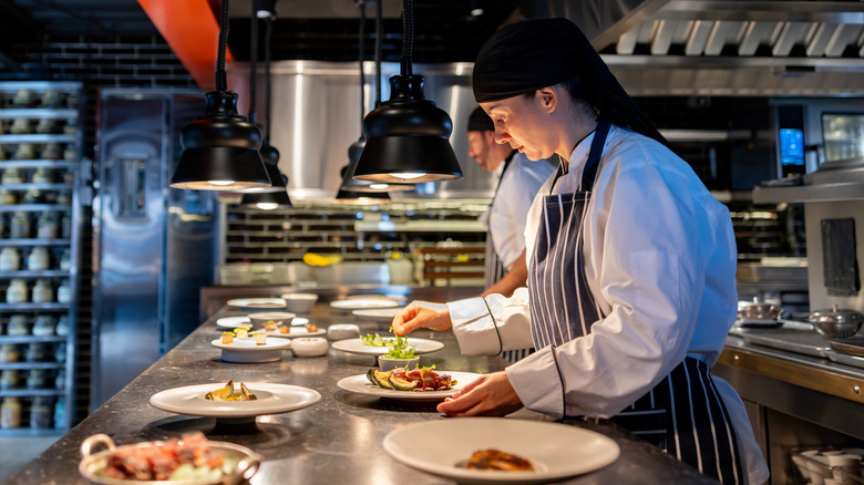 A line cook prepping plates in a kitchen