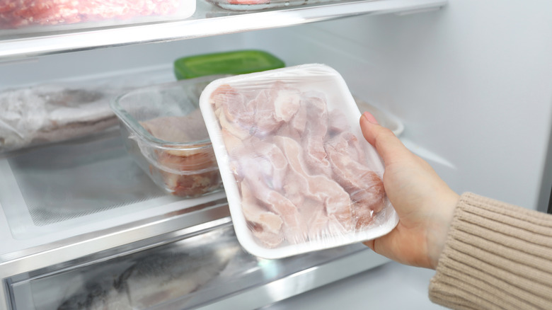 A person taking frozen chicken from a freezer
