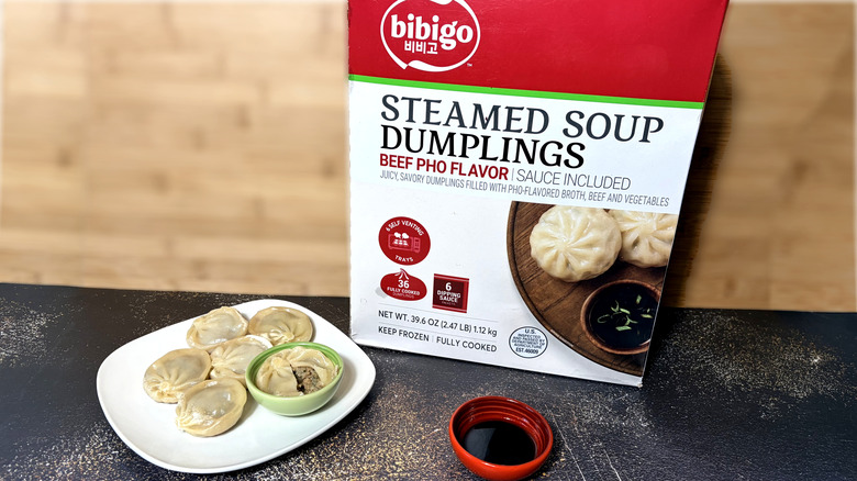Plate of beef soup dumplings with bowl of dipping sauce and package