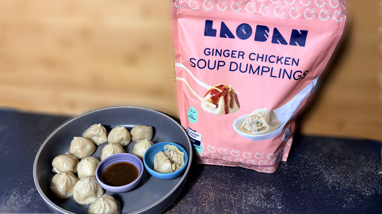 Plate of soup dumplings with bowl of dipping sauce and package