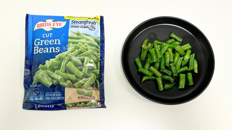 A black plate of green beans next to a bag of Birds Eye Cut Green Beans