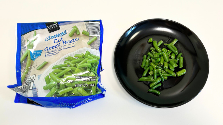 A black plate of green beans next to a bag of Season's Choice Cut Green Beans