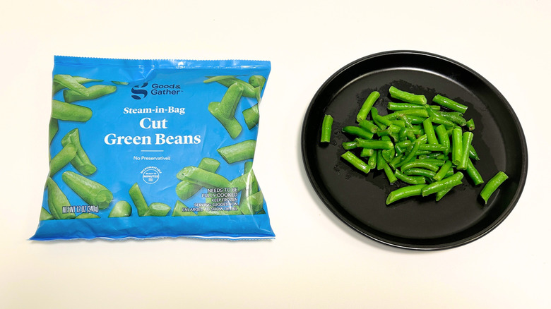 A black plate of green beans next to a bag of Good and Gather Cut Green Beans