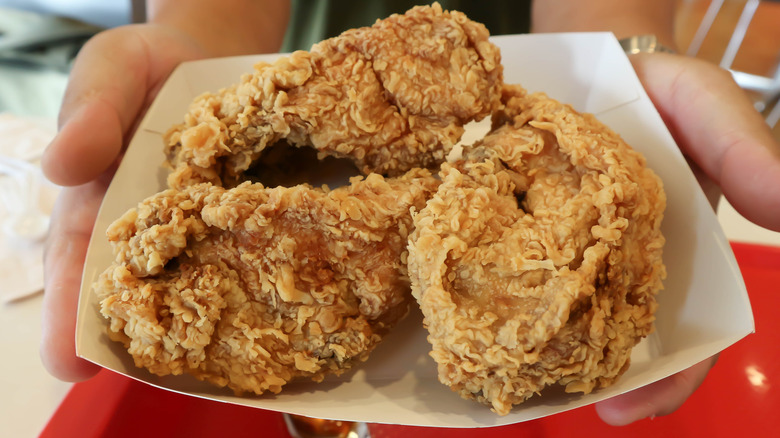 close-up of hands holding paper container of buc-ee's fried chicken