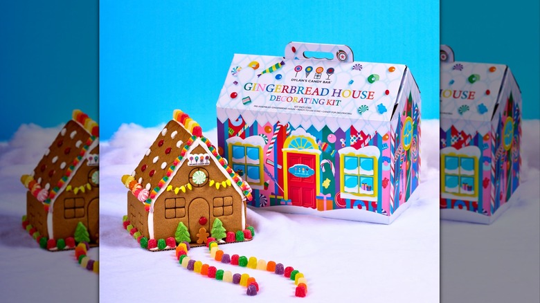 A decorated gingerbread house on fake snow with a house-shaped box for Dylan's Candy Bar's kit in the background.