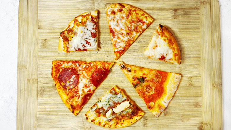 Three slices of pizza alternated with three slices of personal pizza on a cutting board