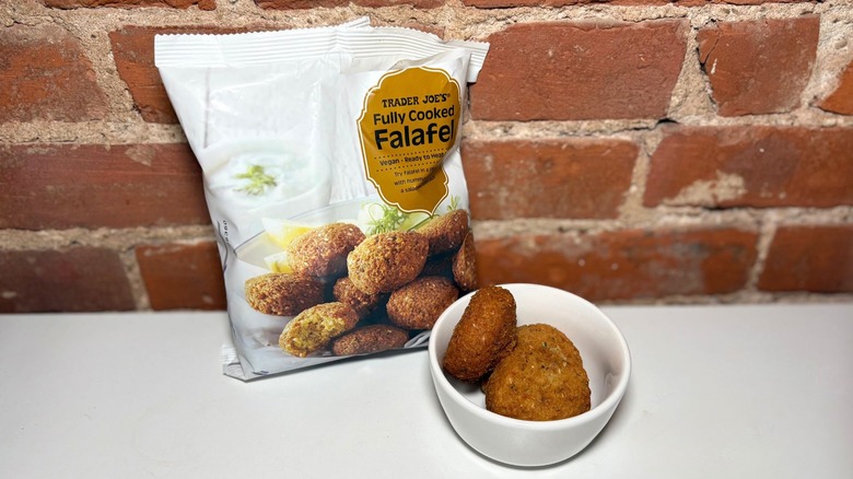 A package and white bowl of Trader Jo's Falafel on a white countertop against a brick background