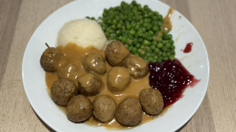 Swedish meatballs with gravy and sides on a white plate