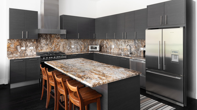 A modern kitchen with gray cabinets and a marble countertop.