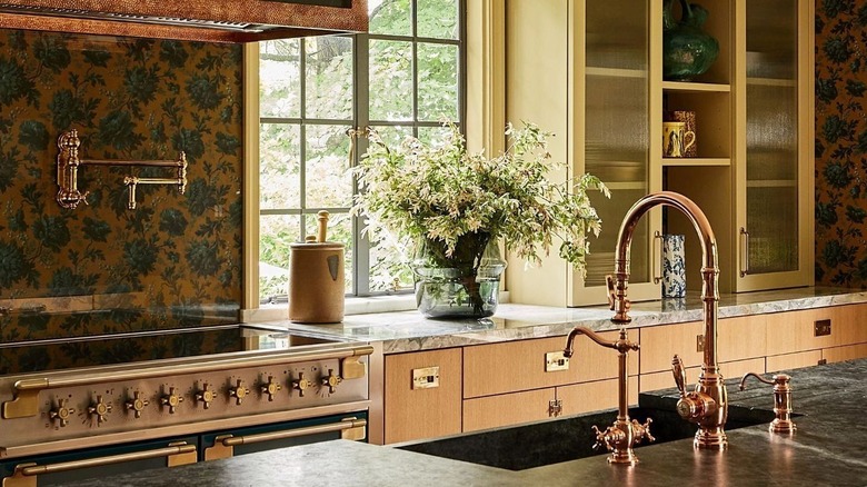 Kitchen with flowery wallpaper and brass finishes