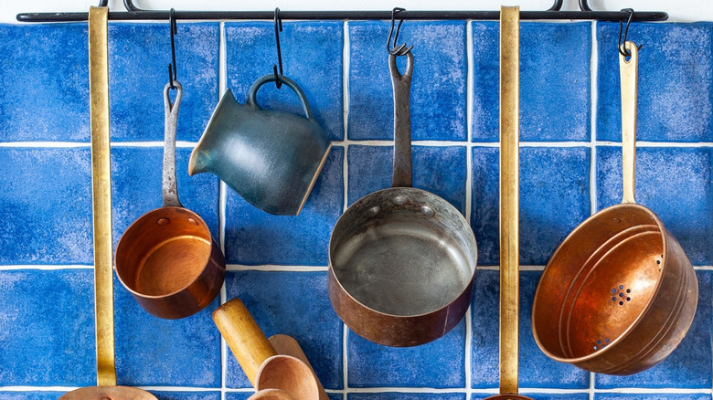Hanging pots and pans against blue tile