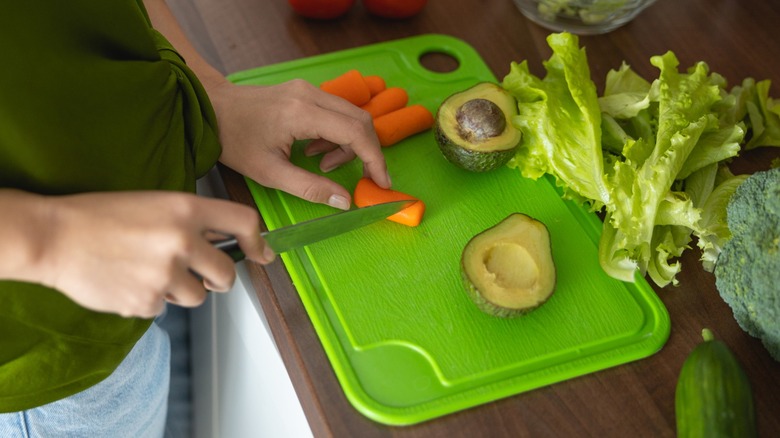 Person cutting vegetables on green plastic cutting board