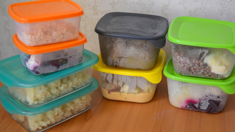 Stacked plastic food storage containers with colorful lids