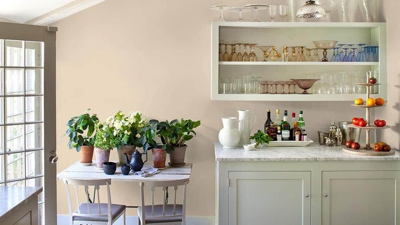 Glidden parchment paint color in a kitchen with open shelves full of glassware and plants on a table.