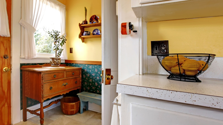 Honey yellow wall color in a kitchen with an antique wooden sideboard and metal bowl with lemons.