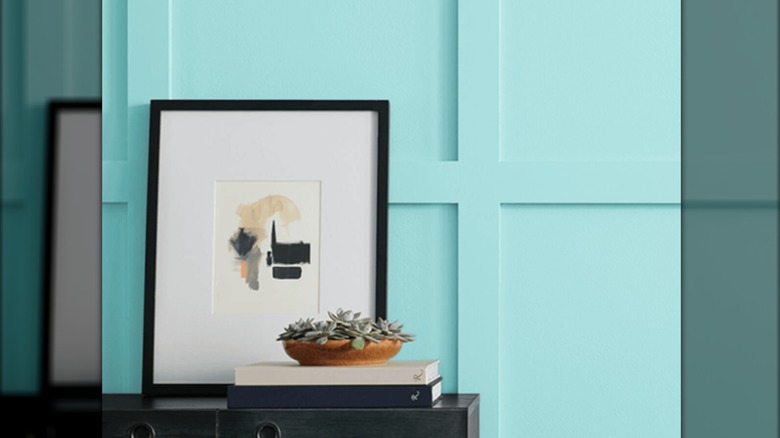 Sherwin Willams Robin's Egg Blue paint on a wall with a black picture frame and styled table in front of it.