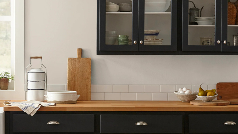 Soft linen warm neutral paint color by Magnolia on a kitchen wall with black cabinets.