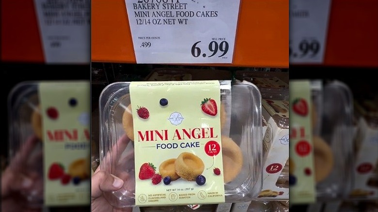 Hand holding container of mini angel food cakes.