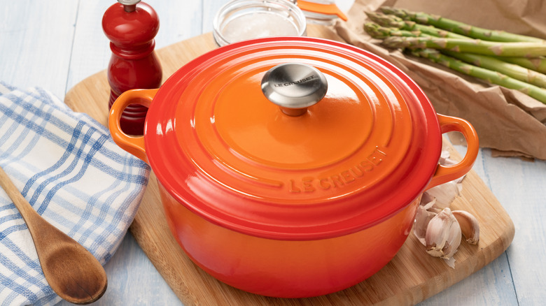 Le Creuset pot in the color Flame on wood cutting board