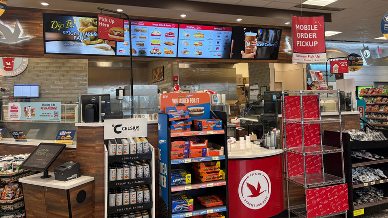 The hot foods section at a Wawa convenience store with digital menu boards overhead