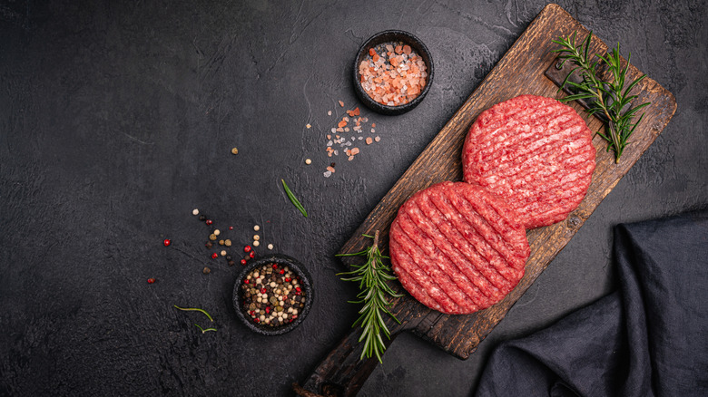 Pre-shaped raw burgers on wooden board