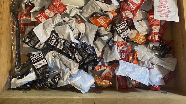 Overhead view of a drawer full of take-out sauce packets
