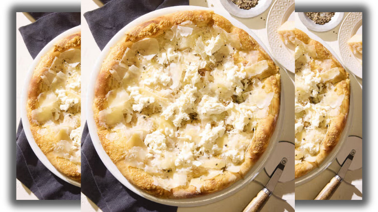 overhead view of a cacio e pepe pizza, featuring big balls of black peppercorns on top