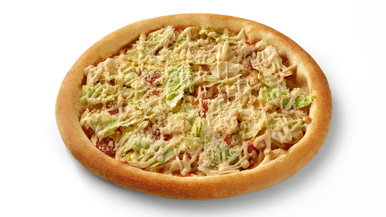 a Caesar salad pizza, a pizza with lettuce, Caesar dressing, and shaved Parmesan cheese on top