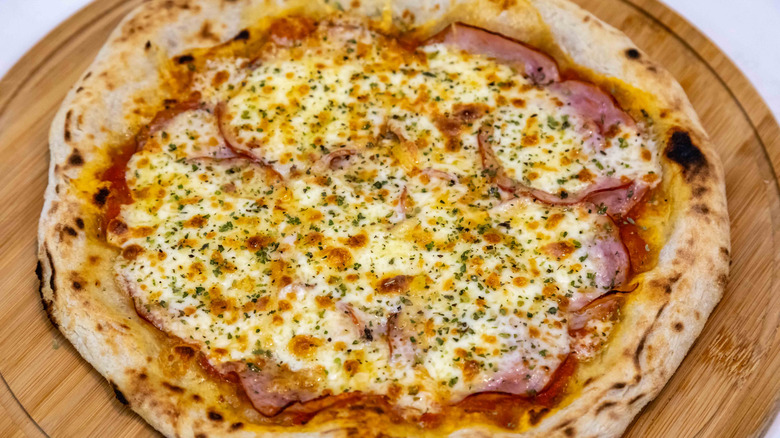 a pizza with Canadian bacon circles curling up from underneath a blanket of cheese