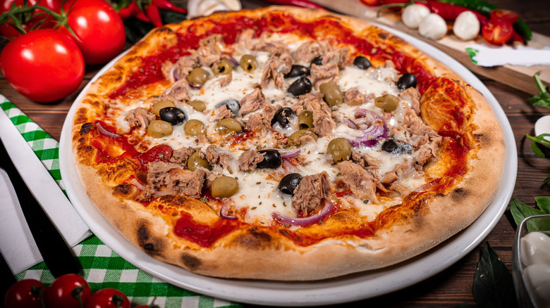 a pizza with tuna, red onions, green olives, and black olives on top