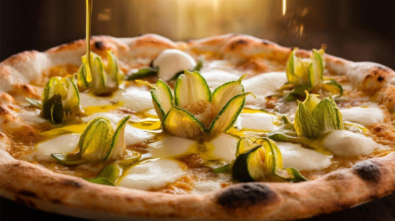 a pizza with circles of melted fresh mozzarella and curled slices of zucchini