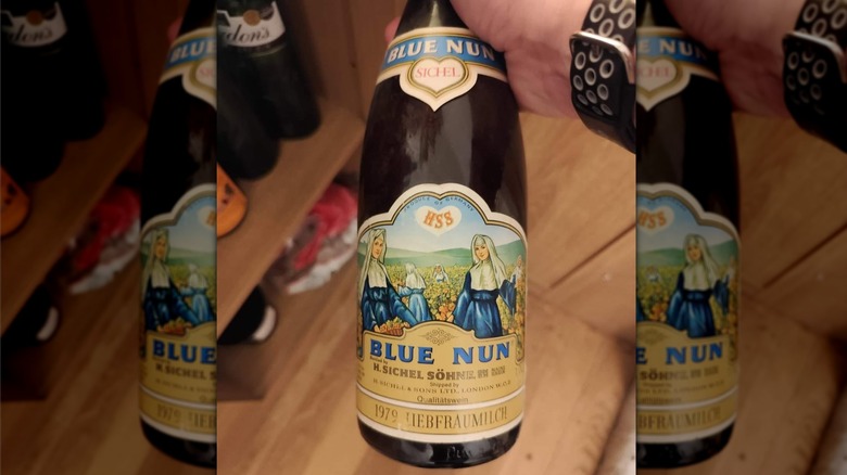 Hand holding bottle of Blue Nun wine