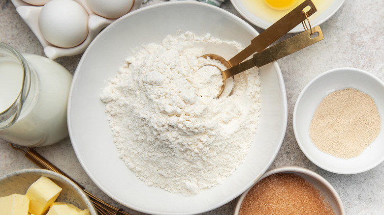 Flour and other baking ingredients in separate bowls on a table