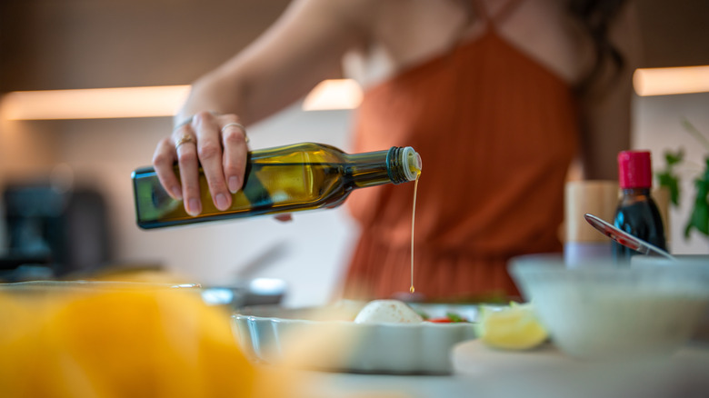Person pouring olive oil on food on a plate