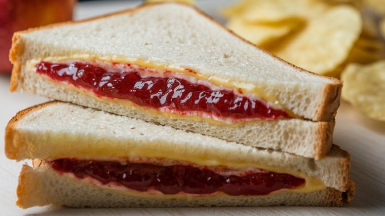 A peanut butter and jelly sandwich on white bread cut in two and stacked on top of each other