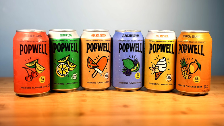 Cans of Popwell prebiotic soda lined up on a table