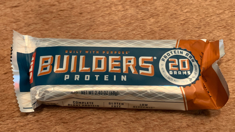A Clif Builders protein bar against a wood table