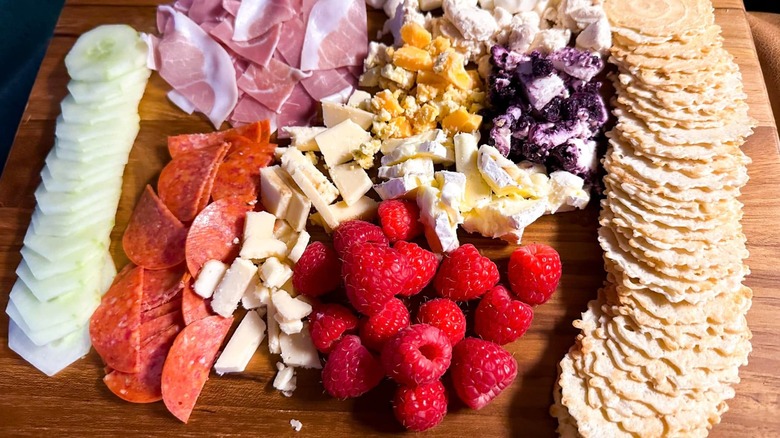 wood board with meats, berries, cheeses, crackers