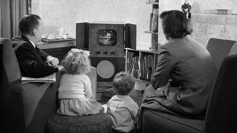 Black and white photo of a family watching a small television set