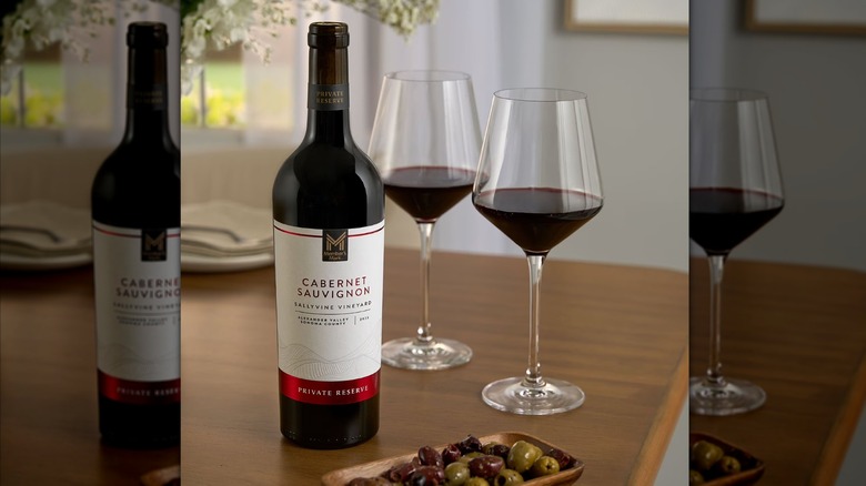 A bottle of Member's Mark cabernet sauvignon with filled wine glasses and an olive tray