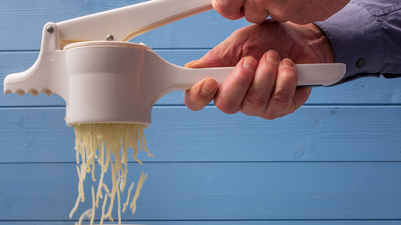 chef pushing potatoes through potato ricer