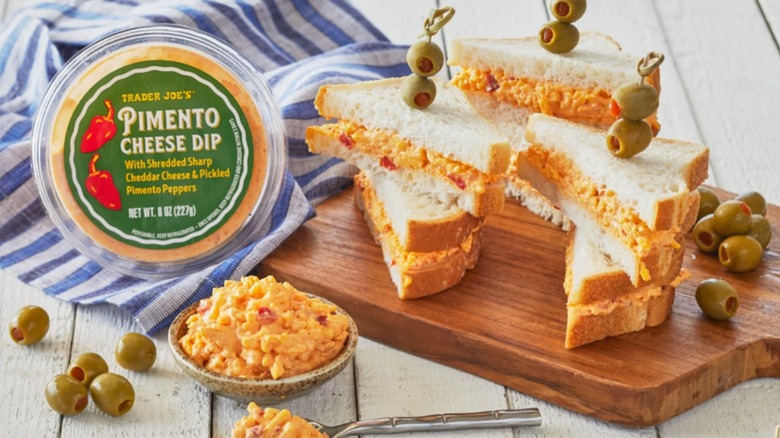 Container of Trader Joe's Pimento Cheese Dip next to sandwiches made with it