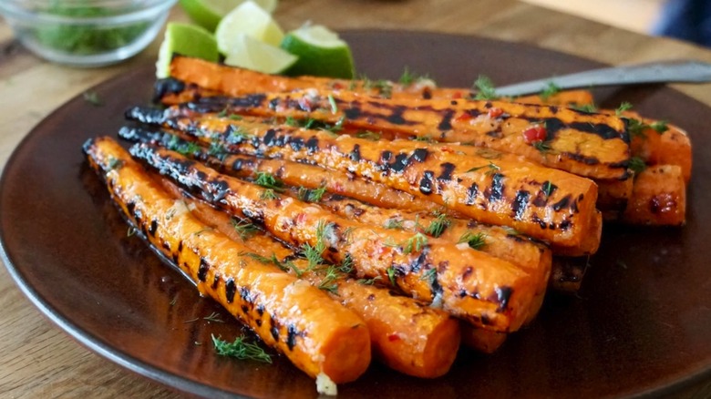 A plate of grilled carrots, dusted with fresh green herbs
