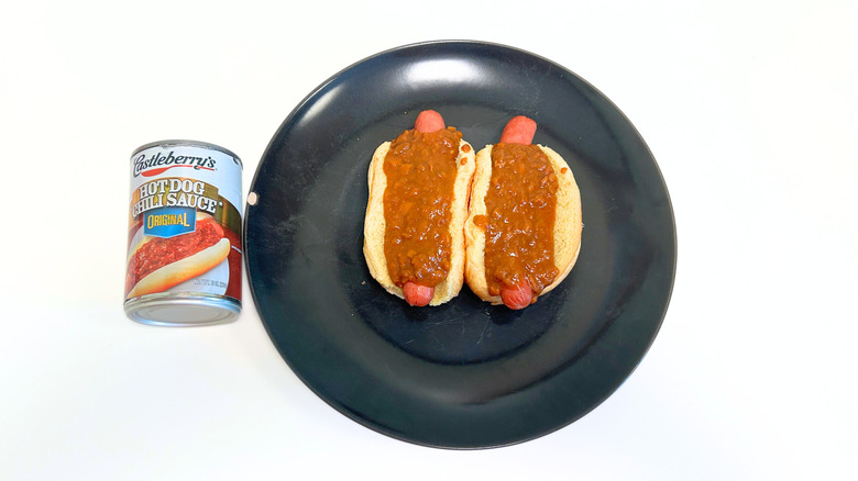 A can of Castleberry's Original Hot Dog Chili Sauce next to a black plate with two chili hot dogs
