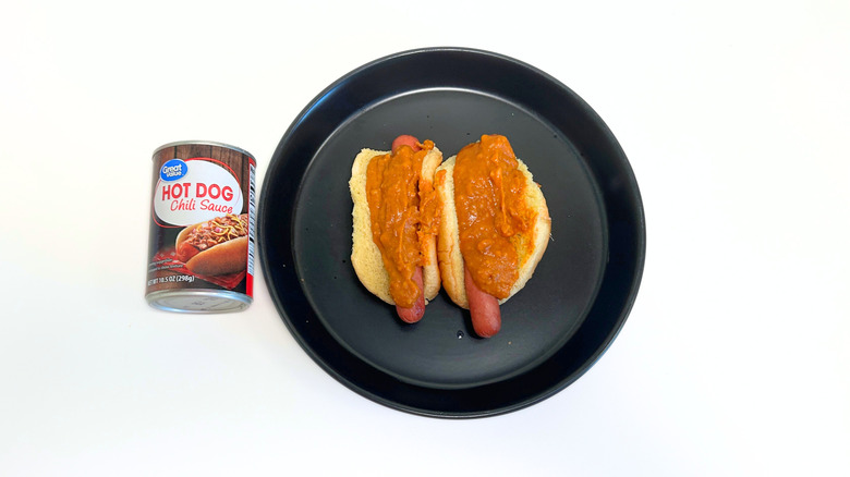 A can of Great Value Hot Dog Chili Sauce next to a black plate with two chili hot dogs