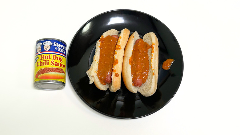 A can of Steve's and Ed's Hot Dog Chili Sauce next to a black plate with two chili hot dogs