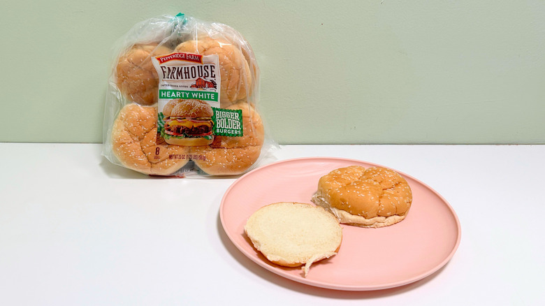 A bag of Pepperidge Farm Farmhouse Hearty White Hamburger Buns next to a plate of hamburger buns